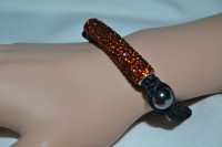 Bracelet fashion tube en strass miel avec perles de verre grises sur cordon noir.